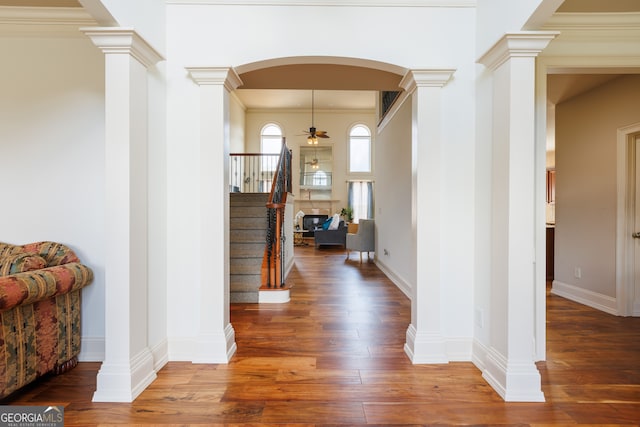 foyer featuring a ceiling fan, arched walkways, wood finished floors, and stairway
