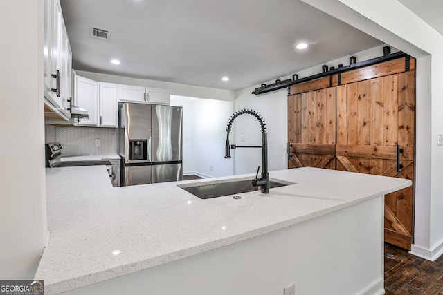 2195 Penelope St NW, Atlanta, GA 30314 - kitchen with appliances with stainless steel finishes, a barn door, dark wood-style flooring, white cabinets, and light stone countertops