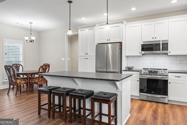 1515 Cabin Creek Trl, Griffin, GA 30223 - kitchen featuring white cabinetry, appliances with stainless steel finishes, wood finished floors, and a kitchen breakfast bar