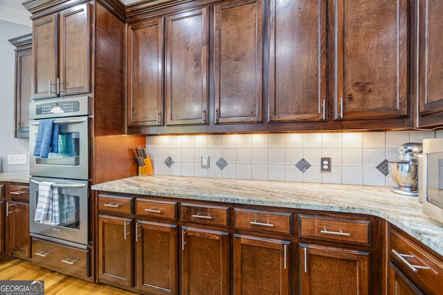 160 Evans Dr, Bogart, GA 30622 - kitchen featuring double oven, light wood-style floors, light stone counters, tasteful backsplash, and crown molding
