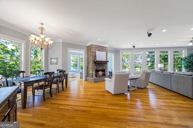160 Evans Dr, Bogart, GA 30622 - living area featuring a stone fireplace, crown molding, light wood-type flooring, a chandelier, and a ceiling fan