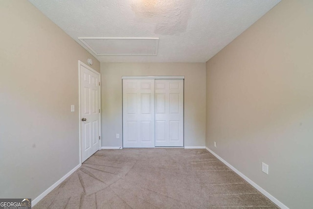 744 Brittany Ct, Stone Mountain, GA 30083 - unfurnished bedroom with a closet, a textured ceiling, attic access, carpet floors, and baseboards