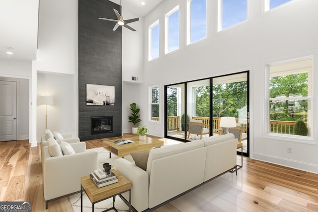 4039 Tallow Pl, Woodstock, GA 30188 - living area featuring a fireplace, baseboards, a high ceiling, a ceiling fan, and light wood-style flooring