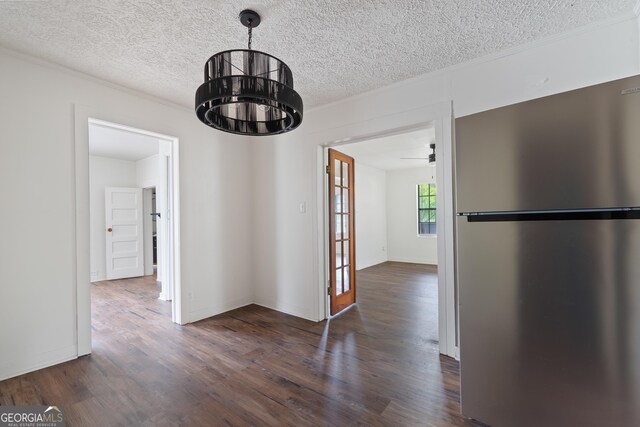 unfurnished dining area featuring crown molding, a textured ceiling, and dark wood finished floors