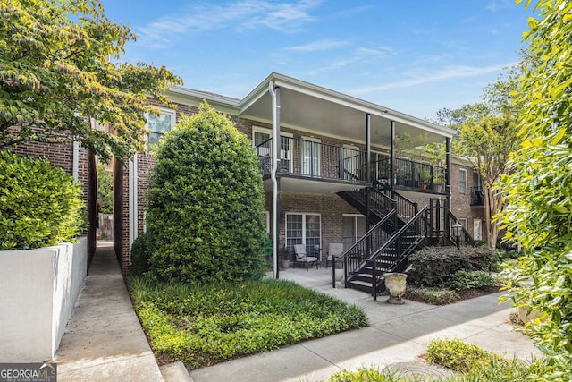 view of front of house with brick siding, stairway, and a patio