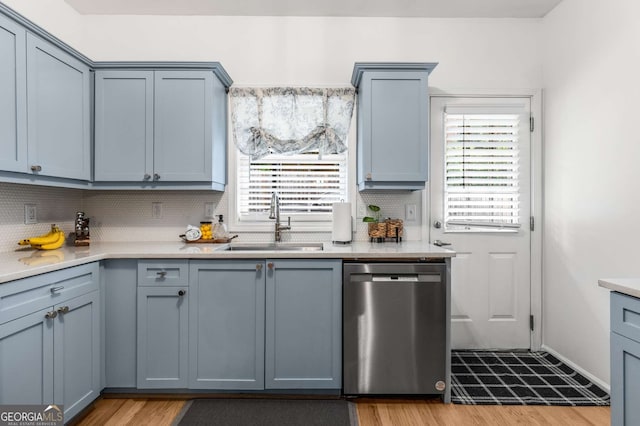 kitchen with a sink, light wood-style floors, a healthy amount of sunlight, tasteful backsplash, and stainless steel dishwasher