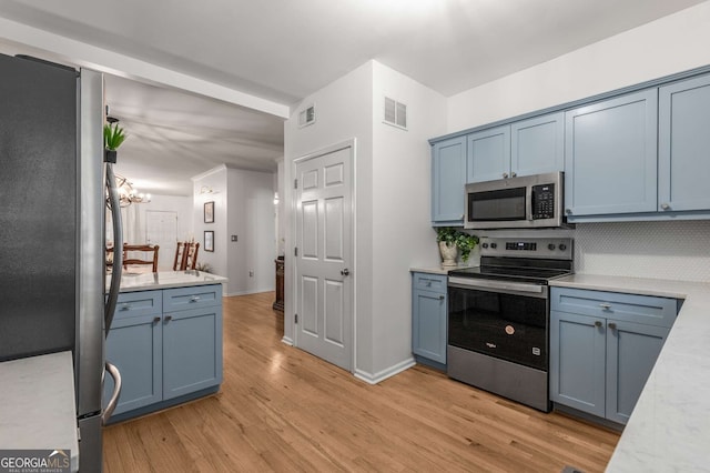 kitchen featuring visible vents, light wood-type flooring, stainless steel appliances, tasteful backsplash, and blue cabinetry