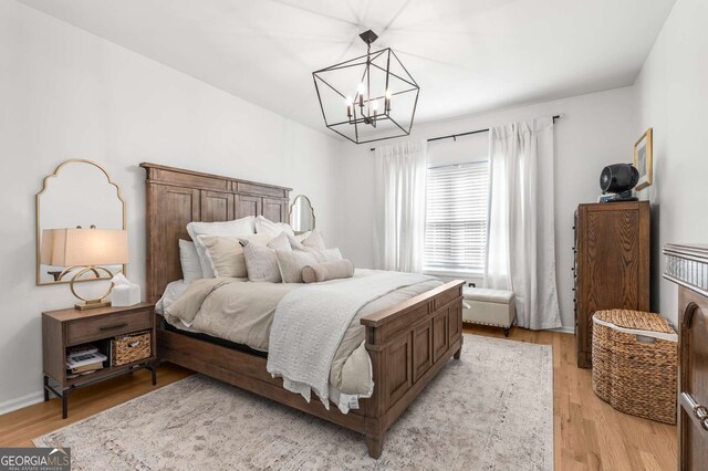 bedroom featuring an inviting chandelier and light wood finished floors