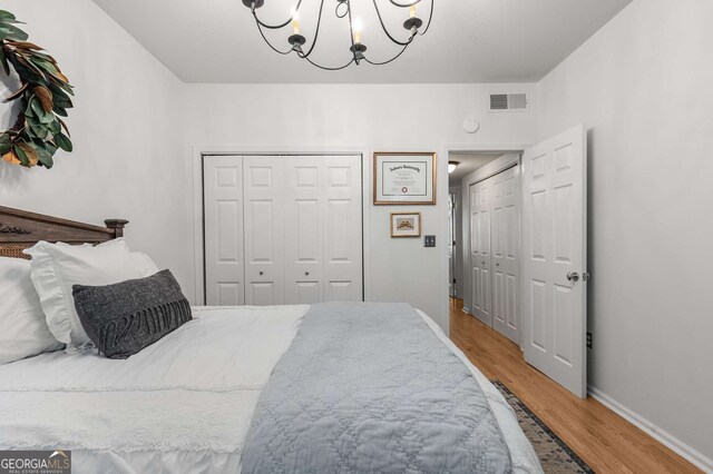 bedroom featuring visible vents, baseboards, a closet, light wood finished floors, and a notable chandelier