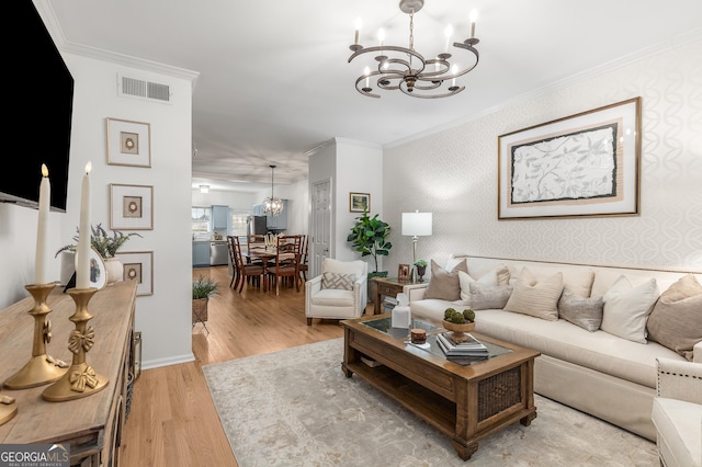 living room with visible vents, ornamental molding, wallpapered walls, light wood-type flooring, and a notable chandelier