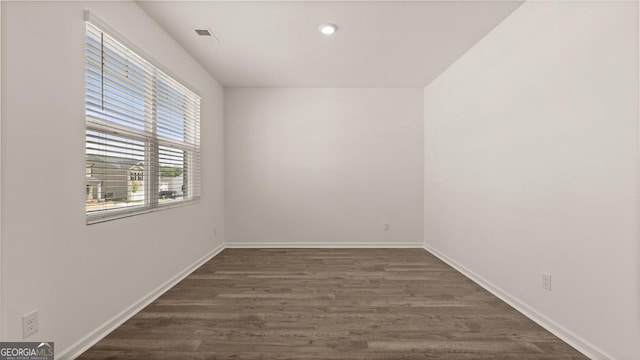 unfurnished room with dark wood-style flooring, baseboards, visible vents, and recessed lighting