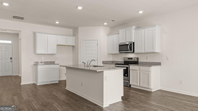 kitchen with a kitchen island with sink, stainless steel appliances, a sink, and dark wood-type flooring