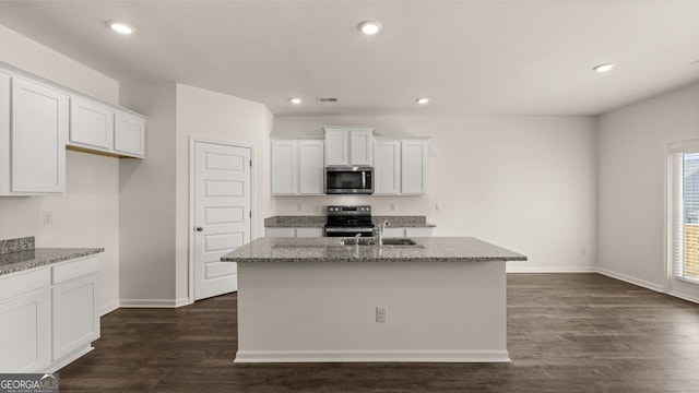 kitchen with a sink, light stone counters, stainless steel appliances, and white cabinetry