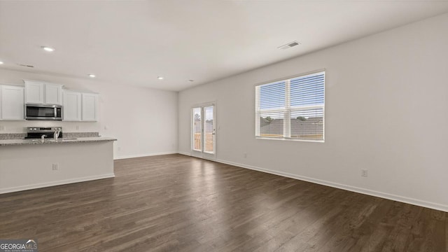 unfurnished living room with recessed lighting, baseboards, dark wood-style flooring, and visible vents