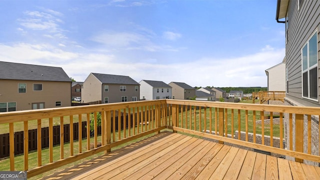 wooden deck featuring a residential view, a lawn, and a fenced backyard