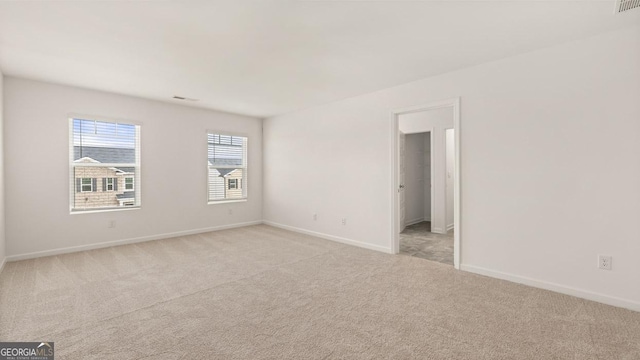 empty room featuring baseboards and light colored carpet