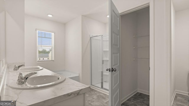 bathroom featuring baseboards, a sink, and a stall shower
