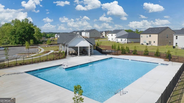community pool featuring a residential view, fence, and a lawn