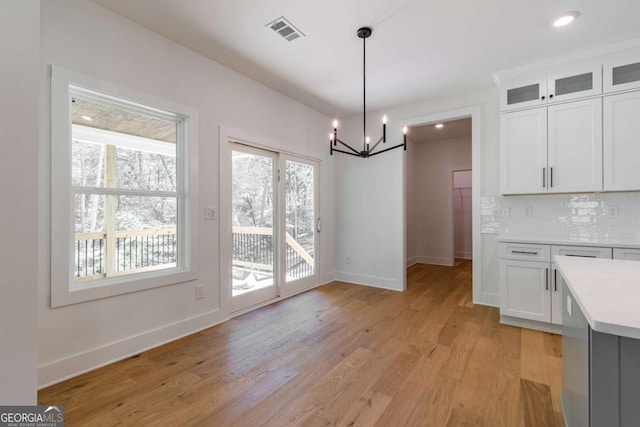 kitchen with appliances with stainless steel finishes, a sink, decorative backsplash, light wood-type flooring, and custom exhaust hood
