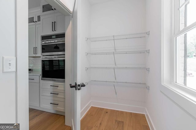 kitchen with a sink, light wood-style floors, light countertops, a fireplace, and dishwasher