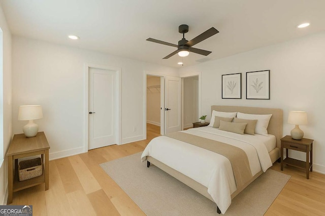 unfurnished bedroom with baseboards, recessed lighting, light wood-style flooring, and a walk in closet