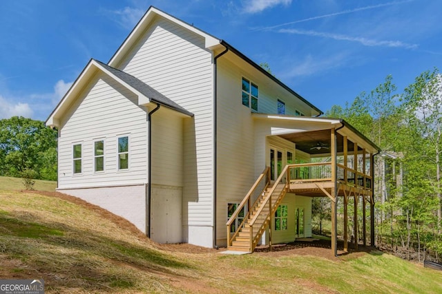 view of property exterior with a lawn, a wooden deck, ceiling fan, and stairway