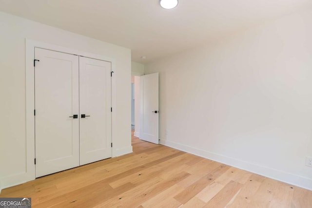 unfurnished bedroom with baseboards, a closet, and light wood-type flooring