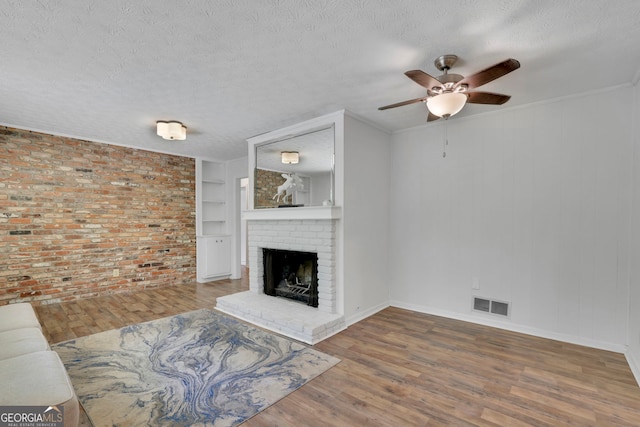 4420 Lake Breeze Dr, Stone Mountain, GA 30083 - unfurnished living room with a ceiling fan, visible vents, a brick fireplace, wood finished floors, and built in shelves