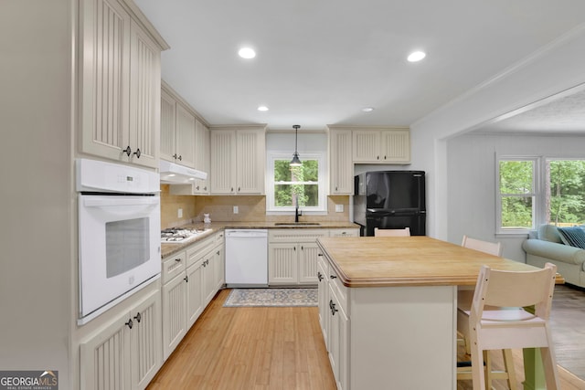 4420 Lake Breeze Dr, Stone Mountain, GA 30083 - kitchen featuring decorative backsplash, white appliances, under cabinet range hood, a sink, and light wood-style flooring