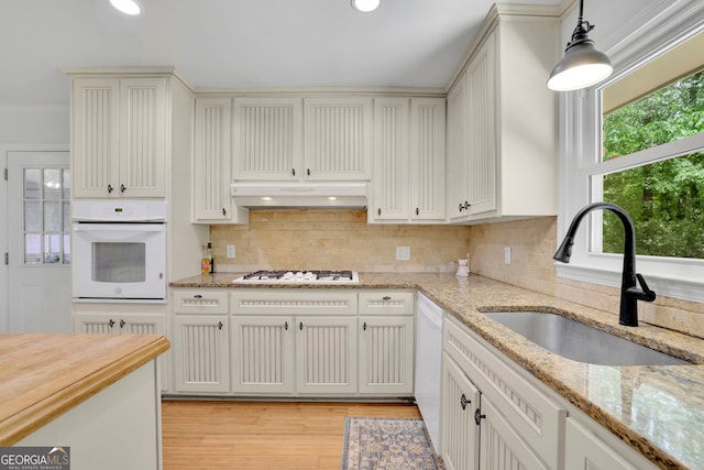 4420 Lake Breeze Dr, Stone Mountain, GA 30083 - kitchen with decorative backsplash, a sink, under cabinet range hood, white appliances, and light wood-style flooring