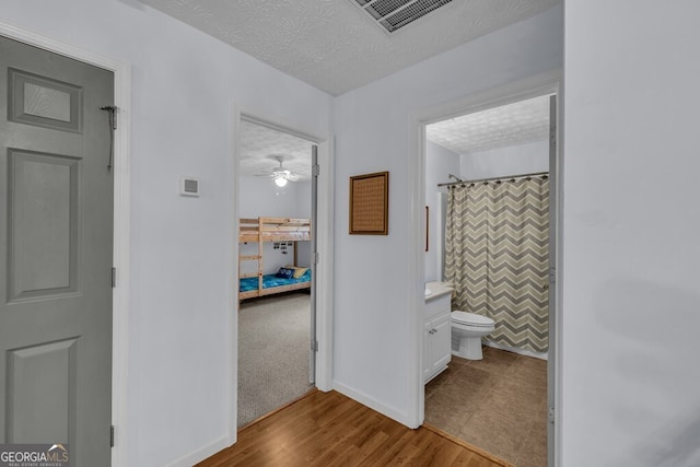 bathroom featuring toilet, a shower with shower curtain, baseboards, wood finished floors, and visible vents