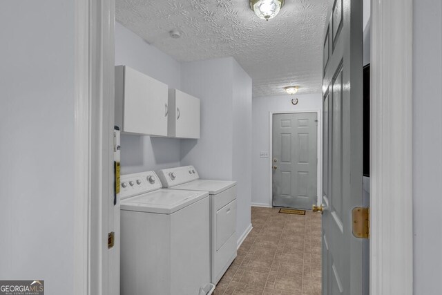 laundry room with separate washer and dryer, a textured ceiling, and cabinet space