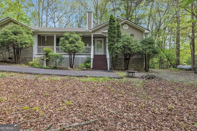 view of front of property with a chimney, a porch, and stone siding