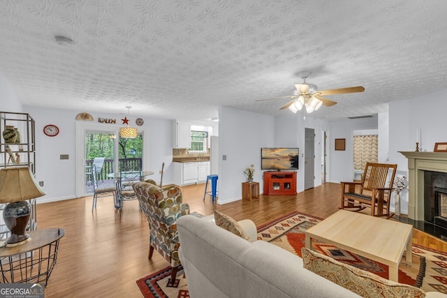 living room with light wood-style floors, baseboards, ceiling fan, and a fireplace