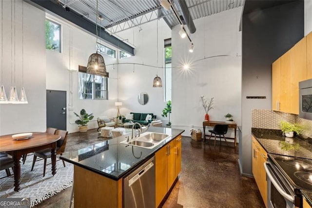 195 Arizona Ave Unit 104, Atlanta, GA 30307 - kitchen with a towering ceiling, brown cabinets, a sink, stainless steel appliances, and an island with sink