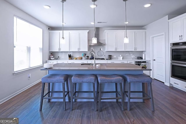 125 Leveret Rd, Locust Grove, GA 30248 - kitchen featuring wall chimney range hood, double oven, decorative backsplash, dark wood finished floors, and baseboards
