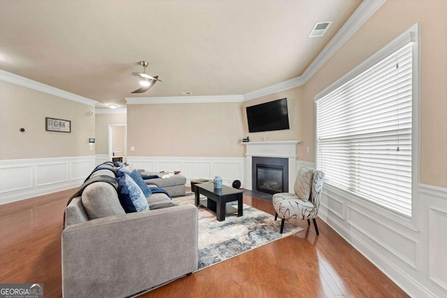 3755 Lake Haven Way, Atlanta, GA 30349 - living room featuring wood finished floors, a fireplace with flush hearth, crown molding, a wainscoted wall, and a decorative wall