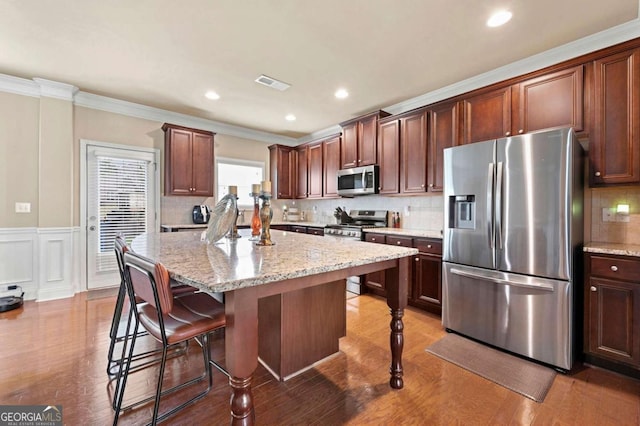 3755 Lake Haven Way, Atlanta, GA 30349 - kitchen with stainless steel appliances, ornamental molding, a kitchen breakfast bar, light stone countertops, and a center island