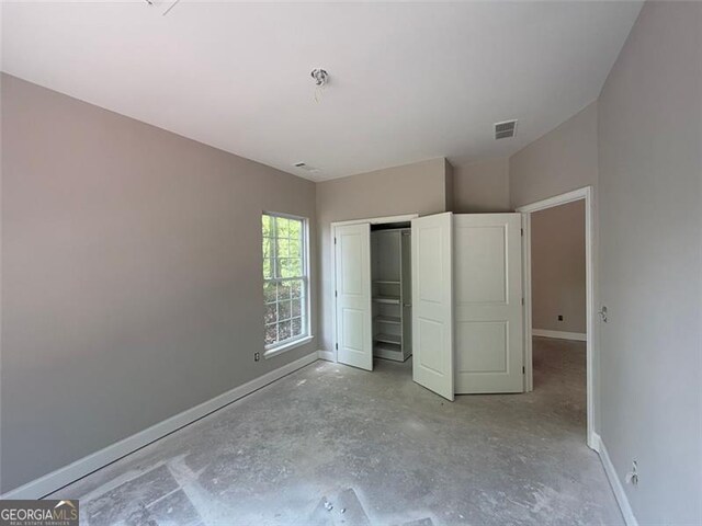 unfurnished bedroom with visible vents, baseboards, concrete flooring, and a closet