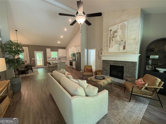 living area featuring a ceiling fan, dark wood-style flooring, a stone fireplace, high vaulted ceiling, and recessed lighting