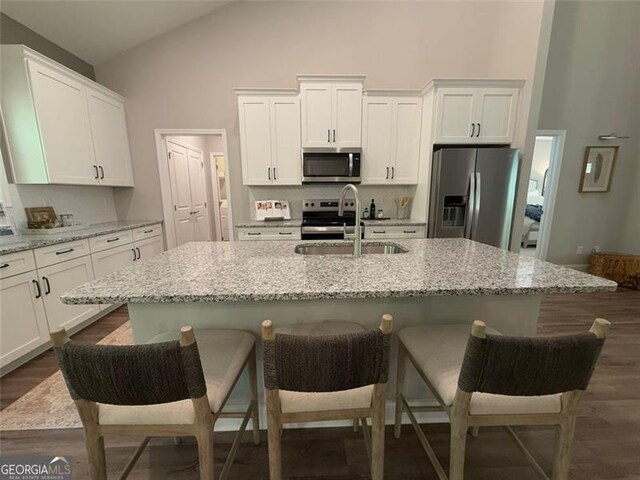 kitchen featuring a sink, white cabinets, high vaulted ceiling, and stainless steel appliances