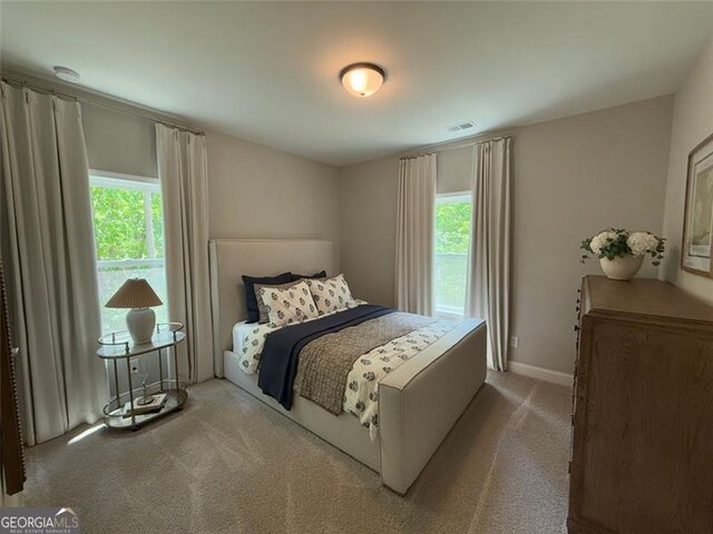 bedroom featuring carpet floors, multiple windows, baseboards, and visible vents