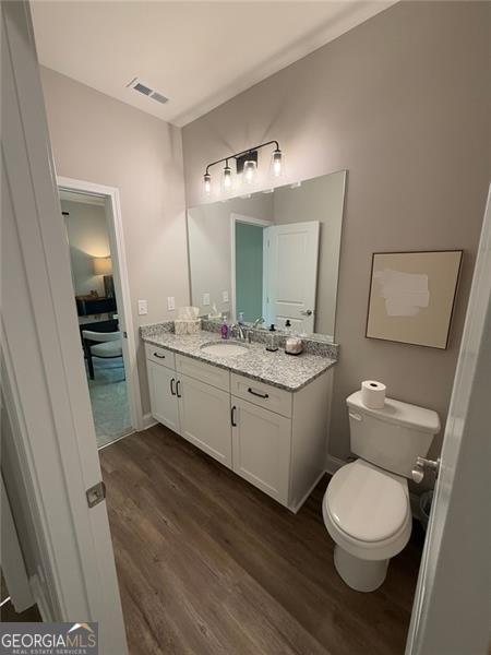 bathroom featuring vanity, toilet, wood finished floors, and visible vents