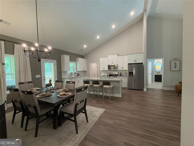 dining space featuring visible vents, dark wood-style flooring, baseboards, high vaulted ceiling, and a chandelier