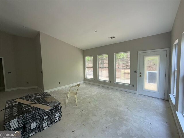 unfurnished living room with plenty of natural light, visible vents, and unfinished concrete floors