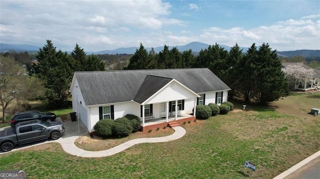 ranch-style home with concrete driveway, a mountain view, a porch, and a front yard