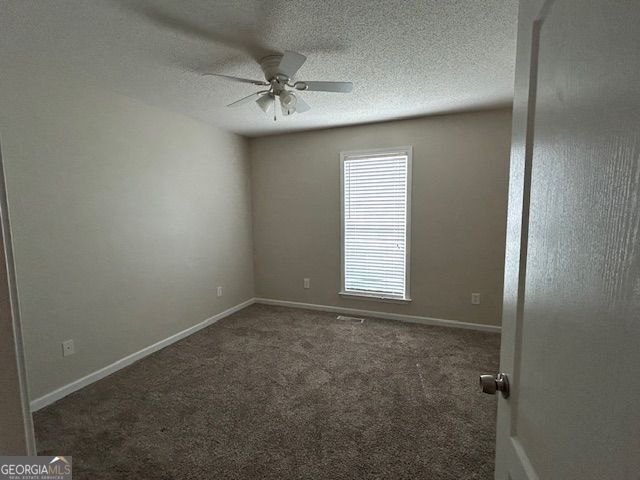 carpeted empty room featuring ceiling fan, baseboards, and a textured ceiling