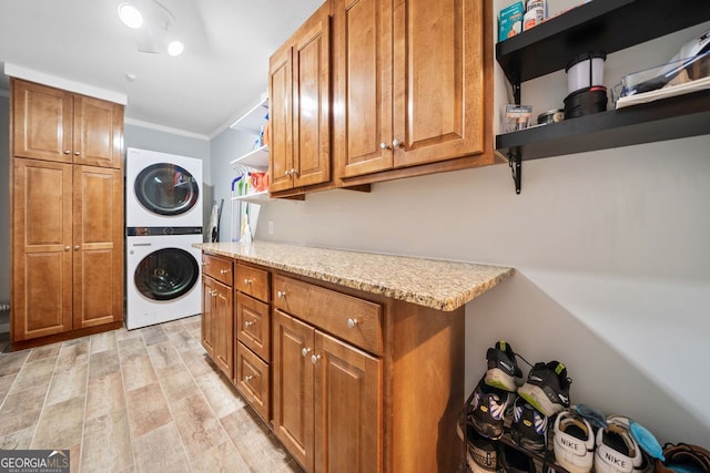 3415 Trickum Rd, Woodstock, GA 30188 - laundry area featuring stacked washing machine and dryer, cabinet space, ornamental molding, and light wood-style flooring