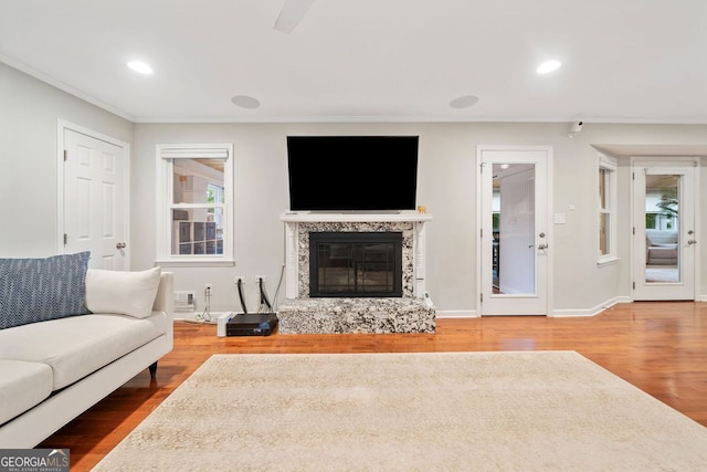 3415 Trickum Rd, Woodstock, GA 30188 - living room with ornamental molding, wood finished floors, a glass covered fireplace, healthy amount of natural light, and recessed lighting
