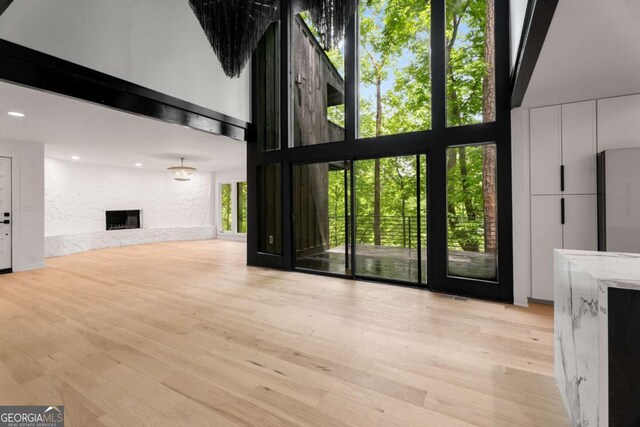 5020 Vallo Vista Ct, Atlanta, GA 30342 - unfurnished living room with a large fireplace, light wood finished floors, recessed lighting, and a towering ceiling